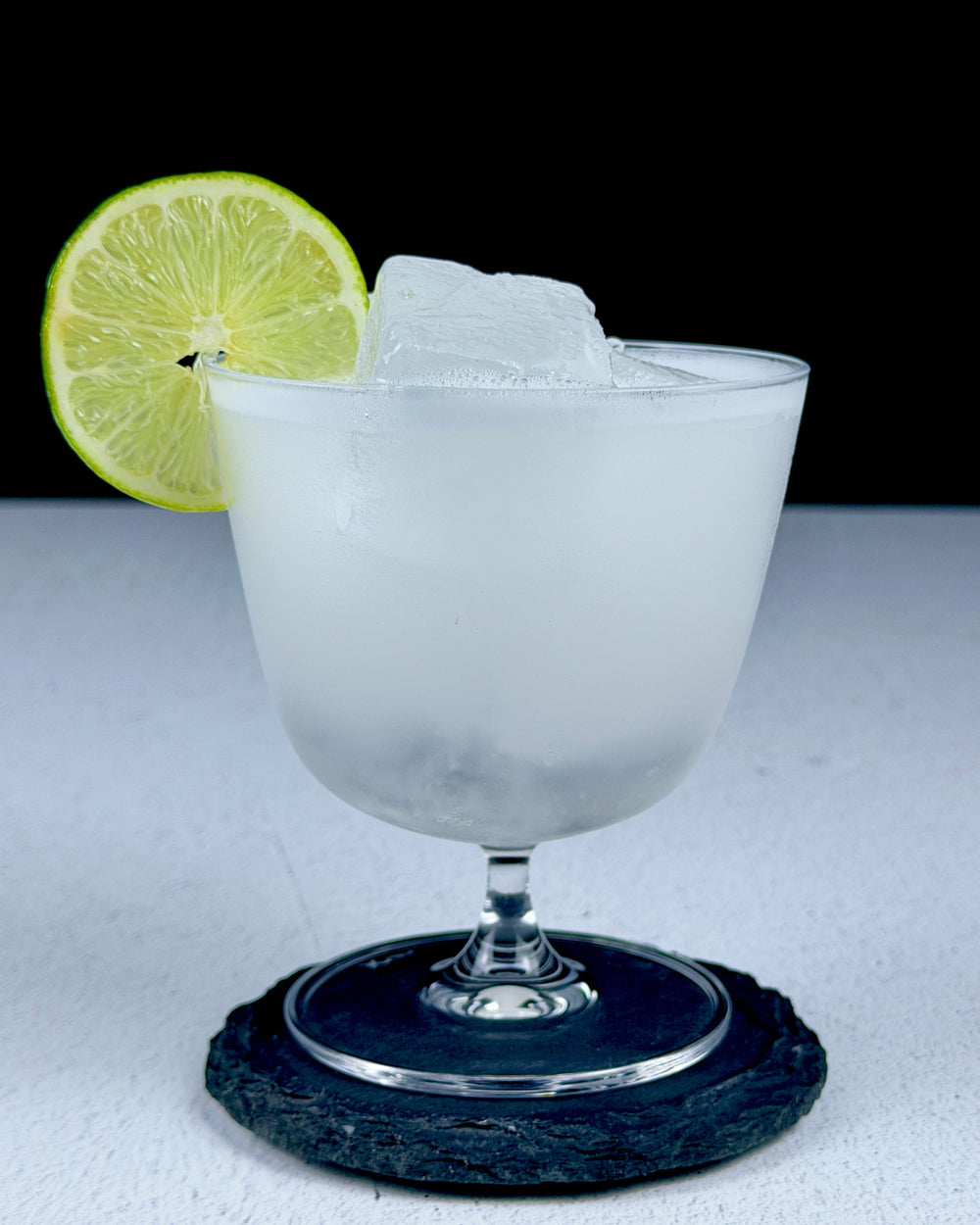 Freshly shaken Cordial Craft Margarita in a stemmed glass with a lime-wheel garnish.